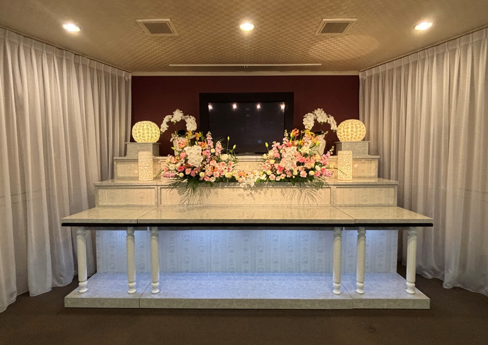 大曲のホール祭壇にピンクの生花を飾るメモリーが大仙市・秋田市のご葬儀向けに用意している壇飾り